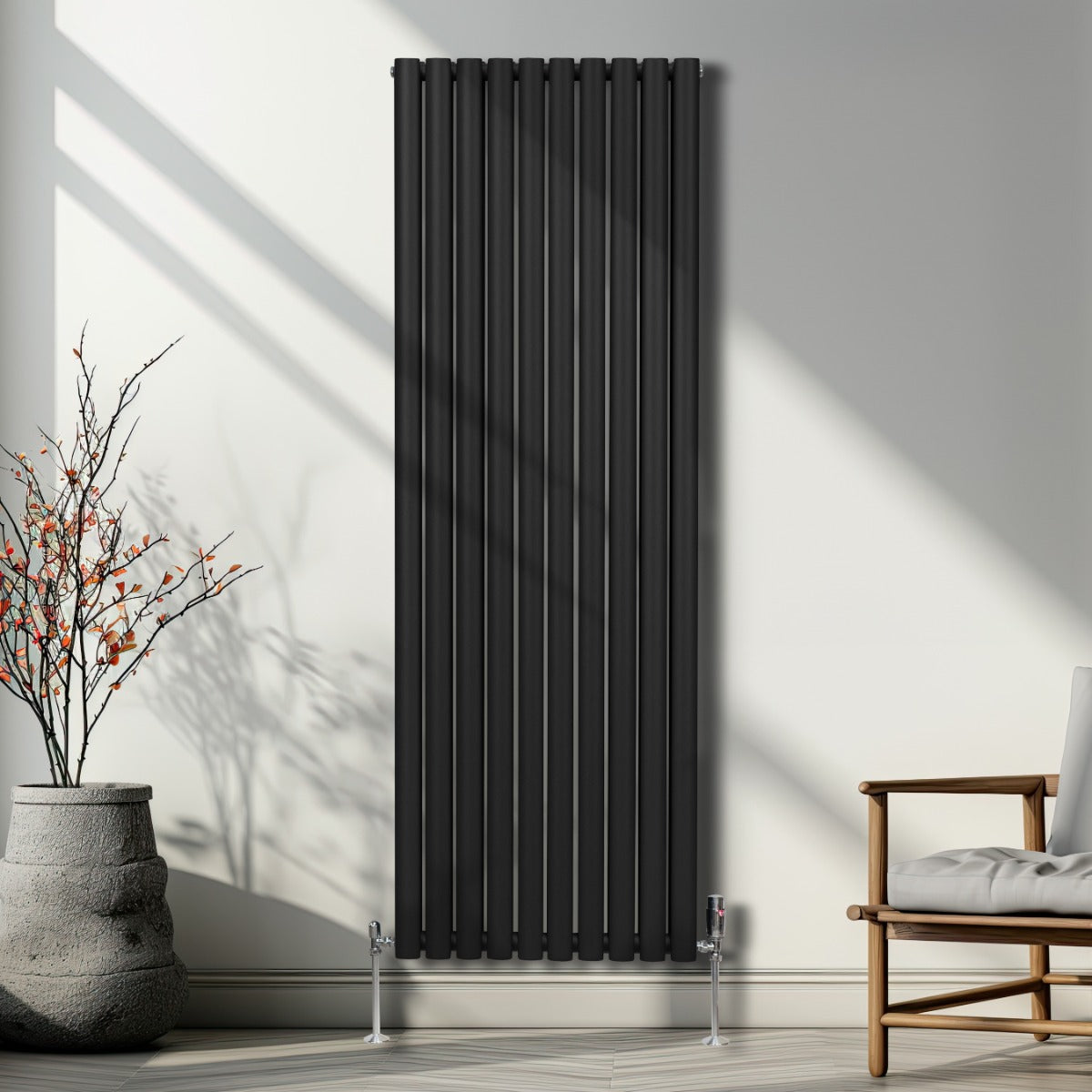 Schwarzer ovaler Röhrenheizkörper mit Chrom-Thermostatventilen, 1800mm x 600mm, an einer hellen Wand, umgeben von minimalistischem Dekor und natürlichem Licht