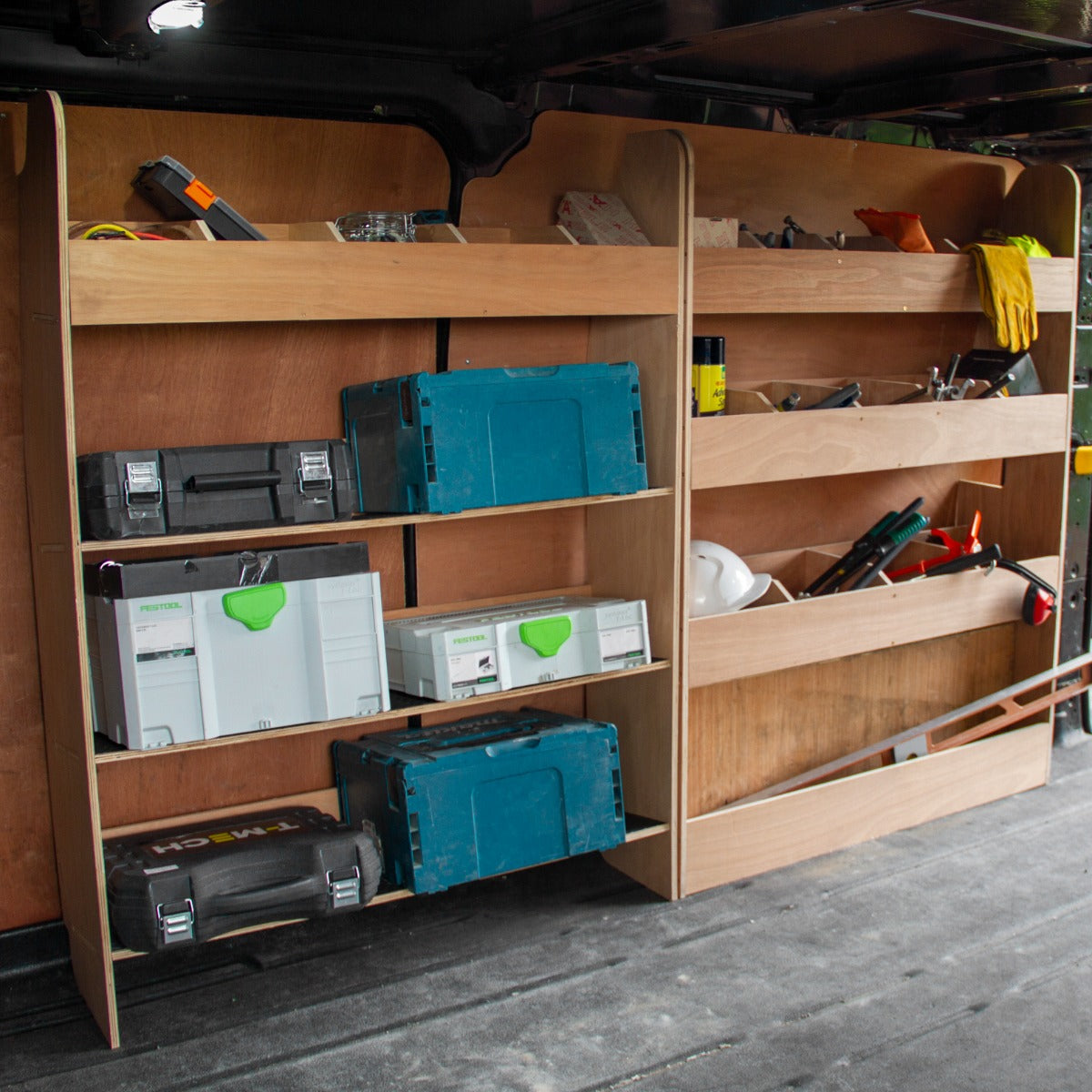 Holzregal mit Werkzeugkästen und verschiedenen Werkzeugen in einem Ford Transit Custom, zeigt eine praktische Fahrzeugeinrichtung für Handwerker