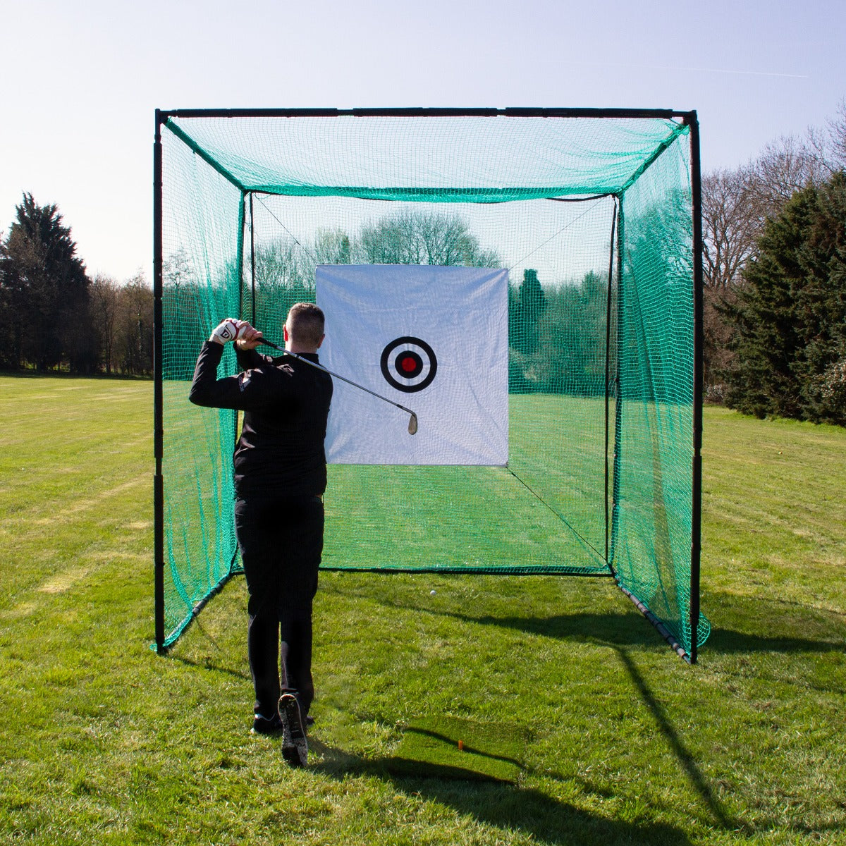 Golfnetz Übungskäfig mit grünem Netz und Zielscheibe, ideal für das Golftraining im Freien, auf einer grünen Wiese unter klarem Himmel