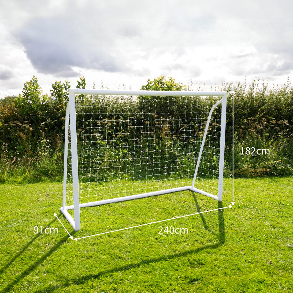 Weißes Fußballtor mit Netz, 2,4m x 1,8m, auf grünem Rasen, umgeben von Bäumen, ideal für Garten- oder Freizeitspiele, inklusive Tragetasche