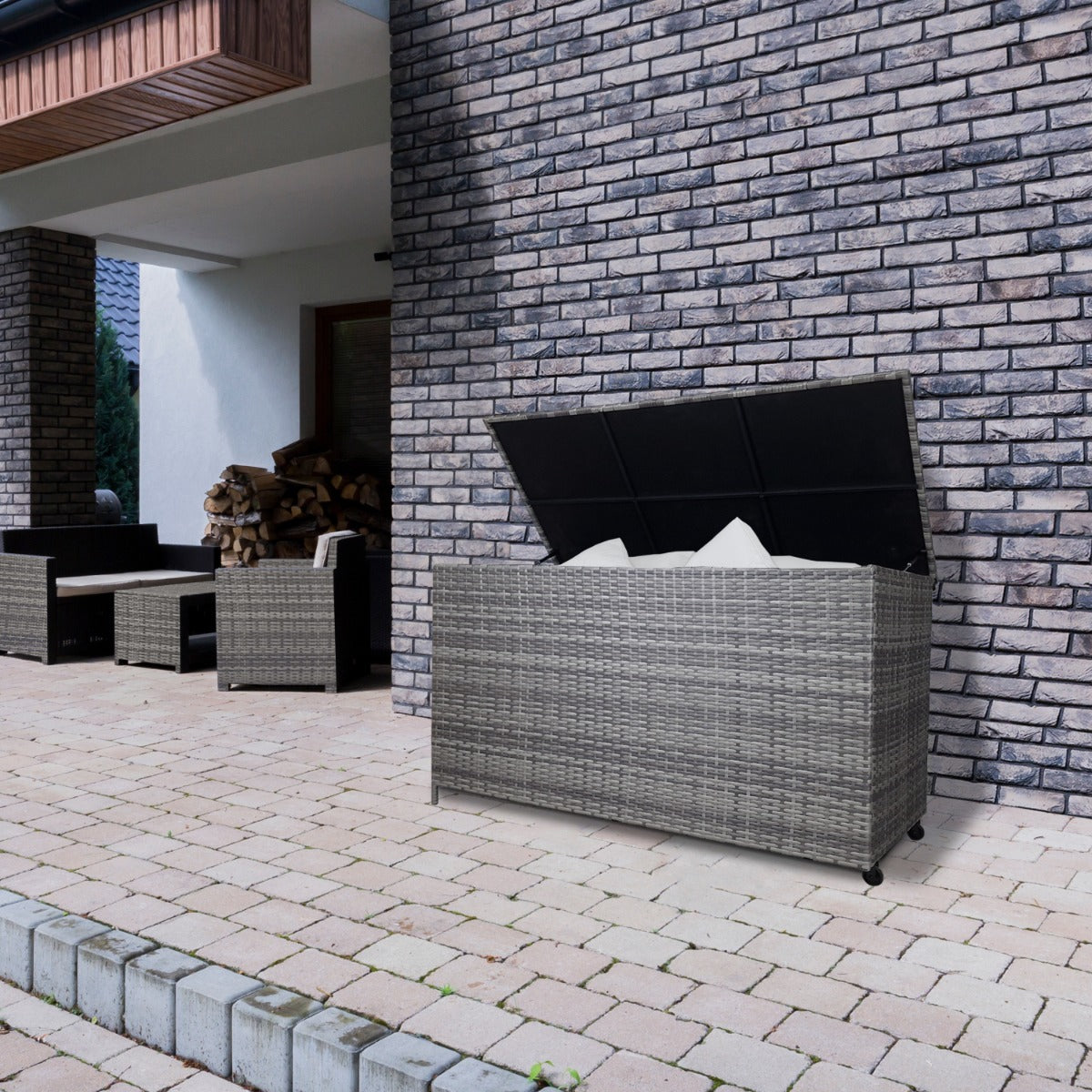 Grau geflochtene Rattan Kissenbox mit einem stabilen Deckel, ideal für die Aufbewahrung von Kissen und Decken im Außenbereich, auf einem gepflasterten Boden