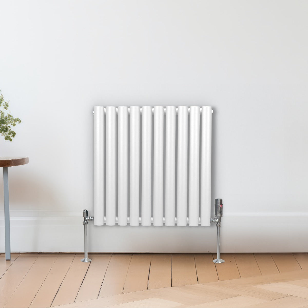 Ovaler Röhrenheizkörper in Weiß, 600mm x 600mm, mit glänzender Oberfläche und vertikalen Röhren, elegant an einer hellen Wand montiert