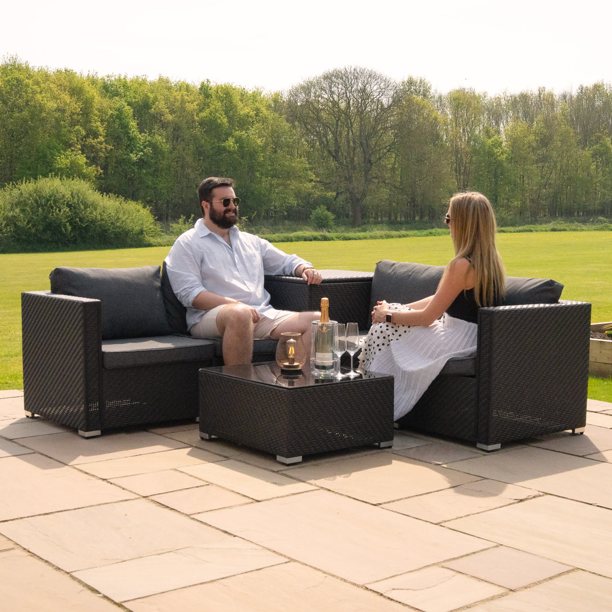 Sechsteiliges Rattan-Möbelset in Schwarz, bestehend aus zwei Sofas und einem Tisch, ideal für entspannte Stunden im Freien, mit grauen Kissen und modernem Design