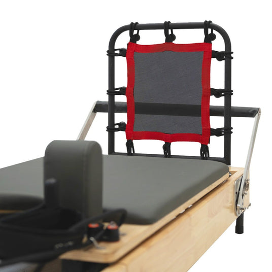 Schwarzer Pilates-Reformer mit rotem Netz und gepolsterter Liegefläche, ideal für Fitness- und Rehabilitationsübungen
