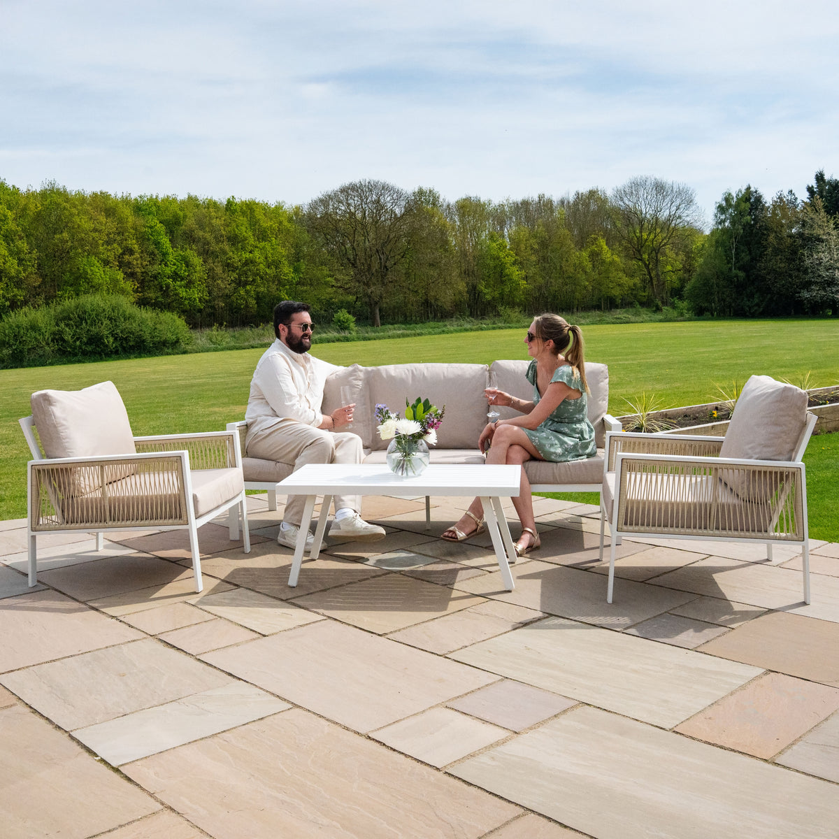Elegante 4-teilige Sofagarnitur aus Aluminium in Weiß mit bequemen, hellen Kissen und einer schwarzen Rattan-Aufbewahrungsbox, ideal für den Außenbereich