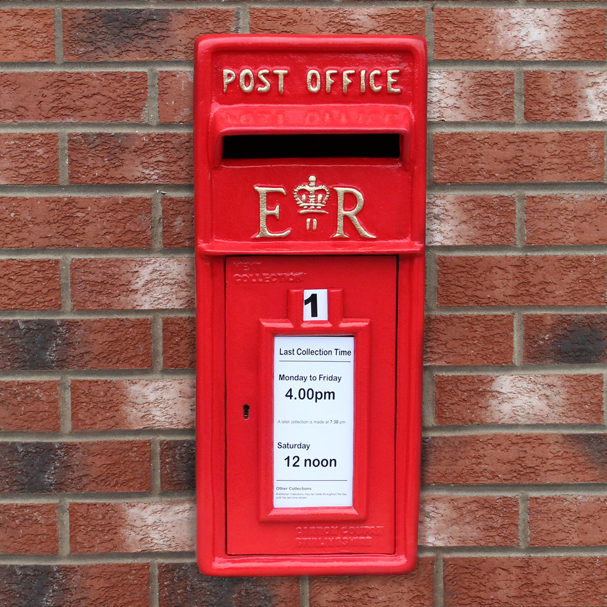 Roter Briefkasten mit Bodenständer, aus robustem Metall, glänzende Oberfläche, mit königlichem Wappen und Sammlungszeiten auf einem weißen Schild