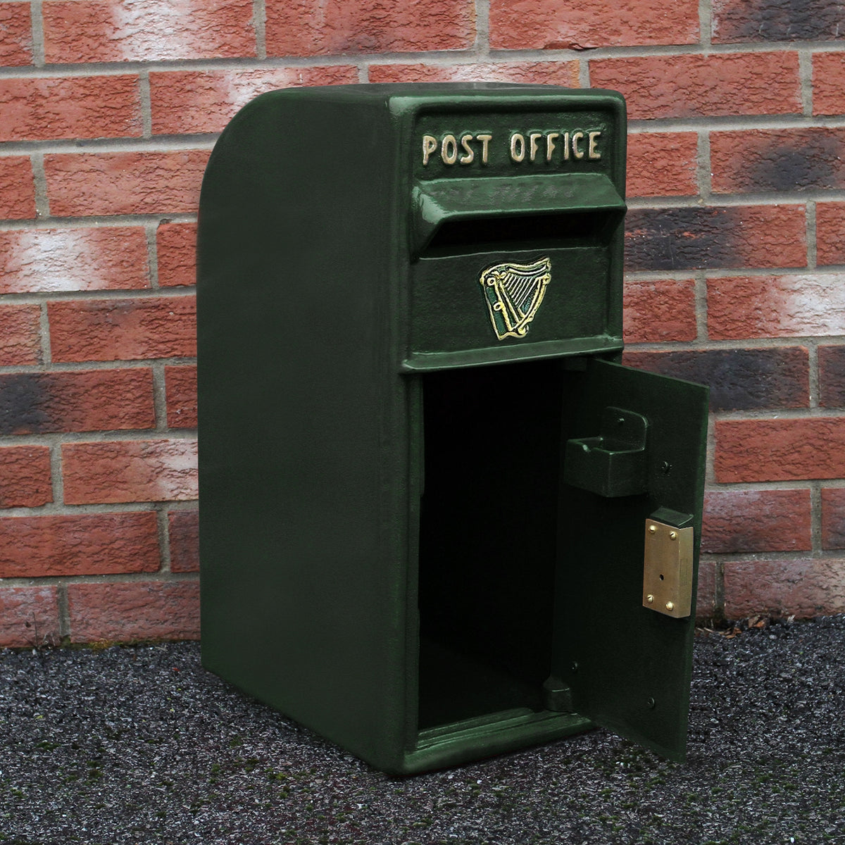 Grüner Briefkasten im irischen Stil mit goldener Harfe und "POST OFFICE"-Schriftzug, aus robustem Material, vor einer roten Ziegelwand