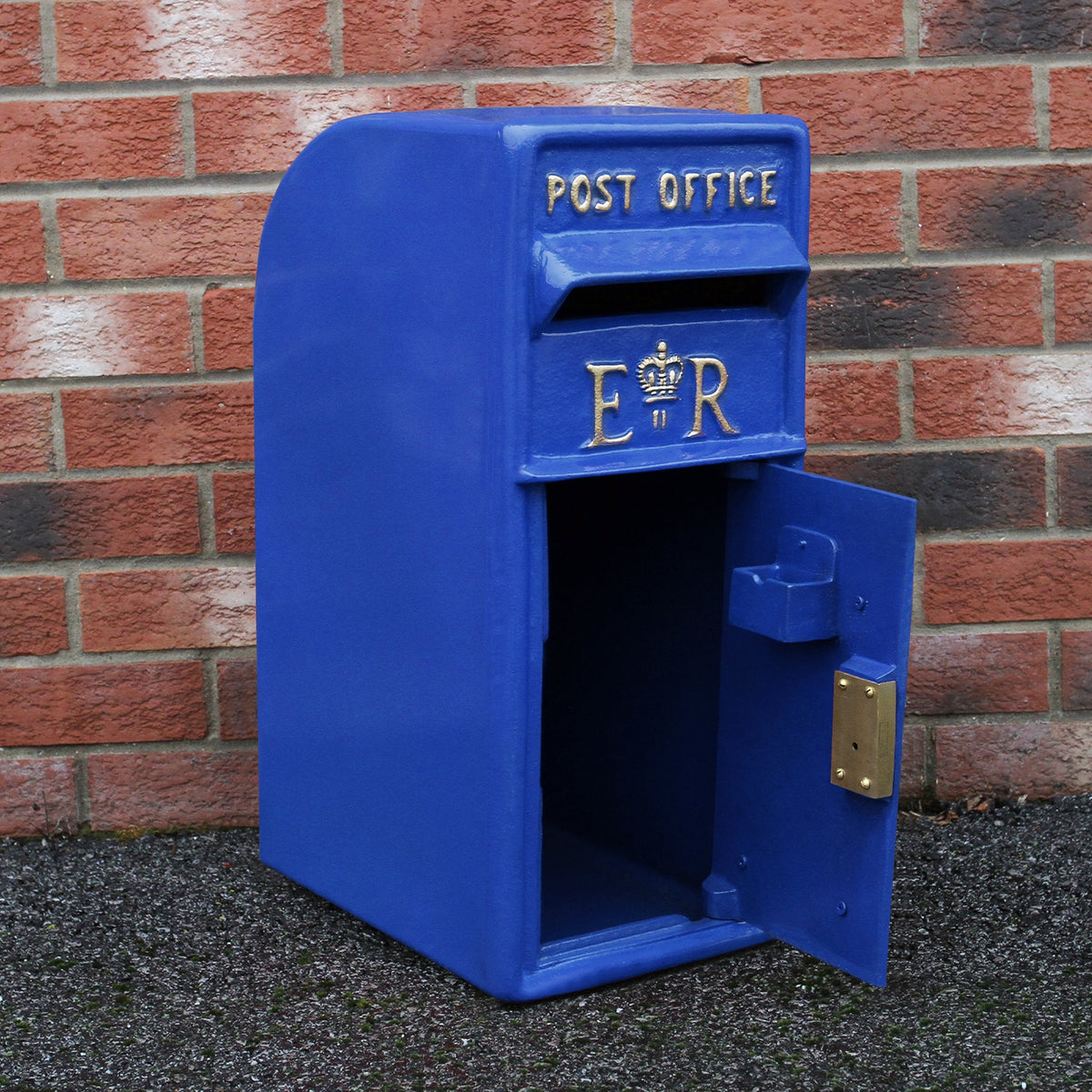 Blauer Briefkasten im schottischen Stil mit goldenen Buchstaben "ER", glänzender Oberfläche und offener Klappe, vor einer roten Ziegelwand platziert