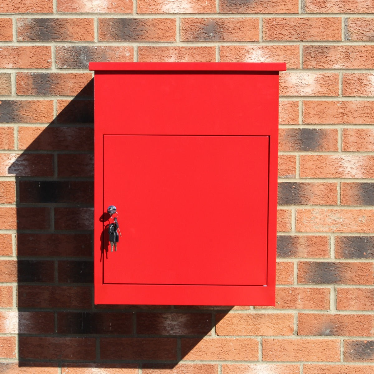 Roter Paketkasten aus Metall mit glatter Oberfläche, rechteckiger Form und einem Schloss, montiert an einer Ziegelwand