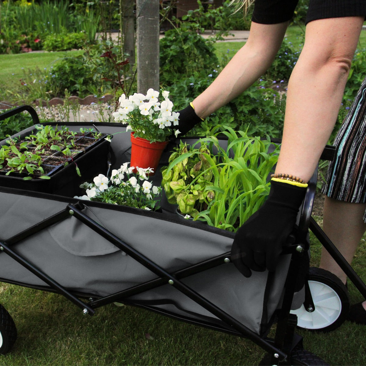 Faltbarer Gartenwagen in Grau, beladen mit bunten Pflanzen und Blumen, robustes Gestell, weiche Textur der Seitenwände, ideal für Gartenarbeit