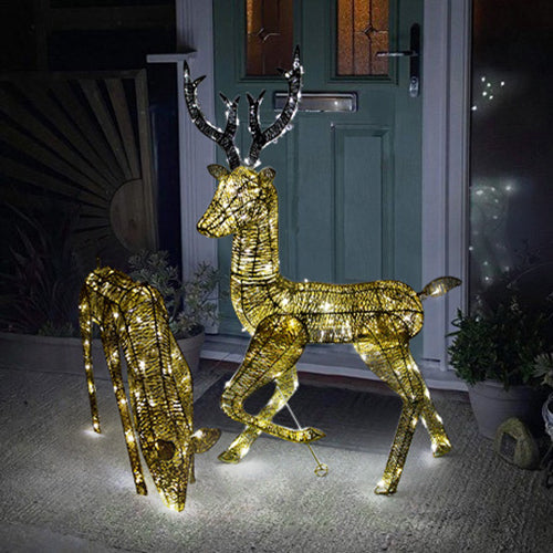Zwei LED beleuchtete Rentiere in Gold, eines 61 cm und das andere 1,2 m hoch, mit funkelnden Lichtern und glitzerndem Geweih vor einer Haustür