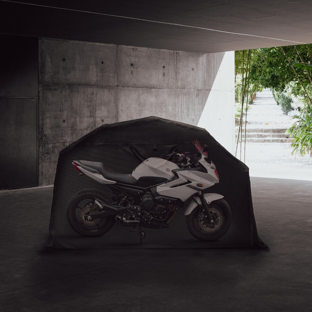 Schwarzes Motorrad Garagenzelt XL mit einem weißen Motorrad, das sicher und geschützt in einem modernen, minimalistischen Raum steht