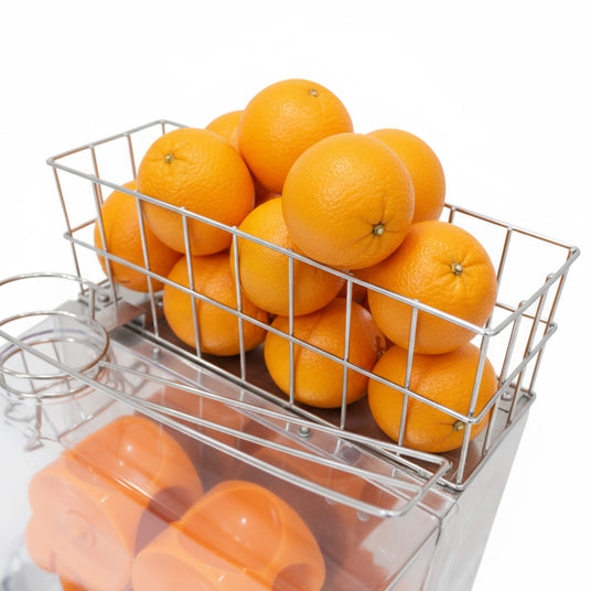 Ein Drahtkorb voller leuchtend orangefarbener Orangen, die frisch und saftig aussehen, auf einem transparenten Behälter mit orangefarbenen Deckeln