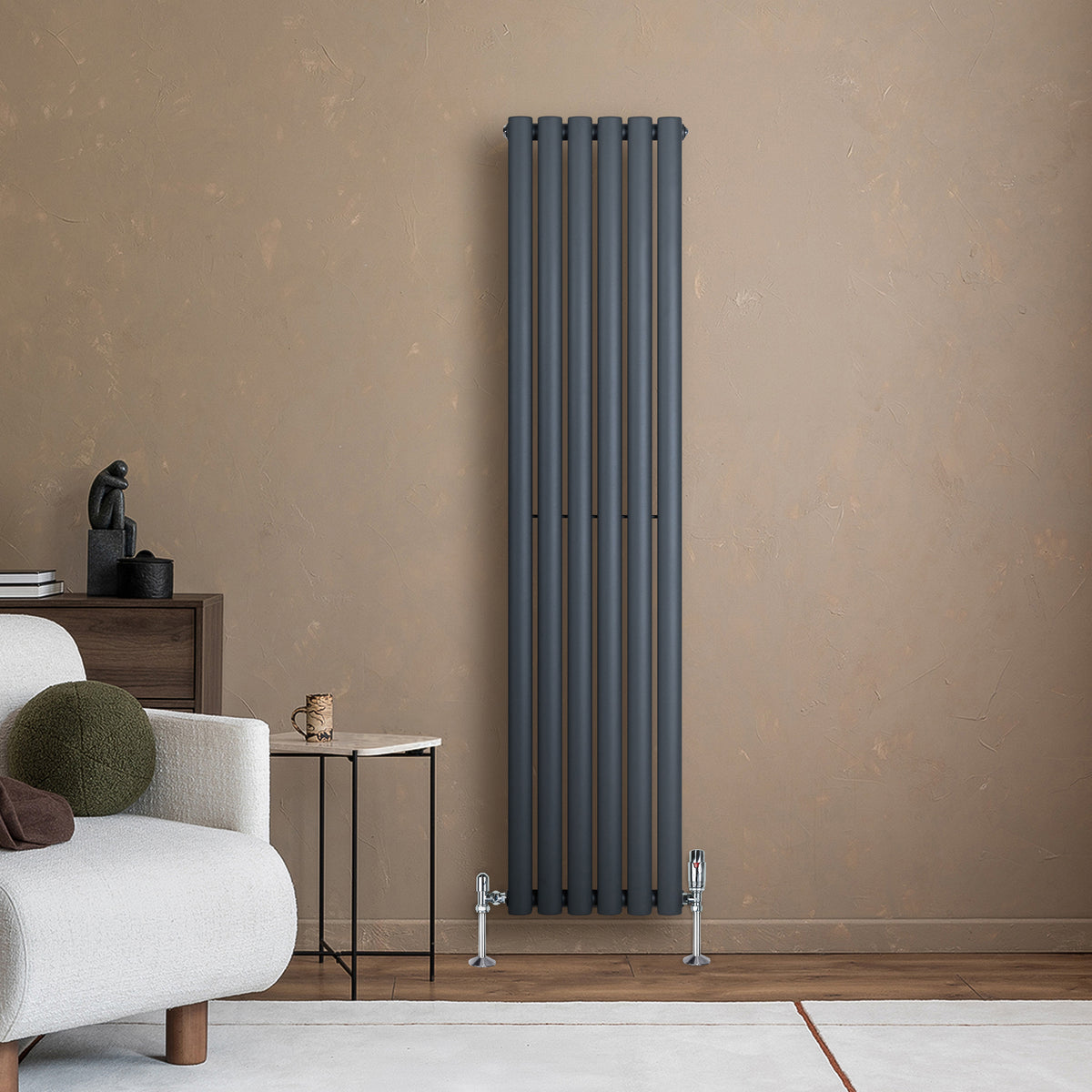 Anthrazitgrauer Gliederheizkörper mit TRV Chromventilen, 1600mm x 360mm, an einer warmen Wand, neben einem modernen Sofa und Beistelltisch