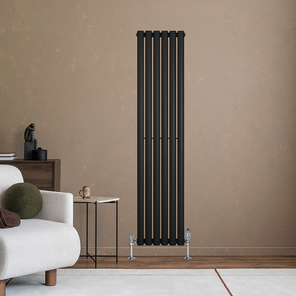 Schwarzer Gliederheizkörper mit TRV Chromventilen, 1600mm x 360mm, vertikal an einer Wand, umgeben von einem modernen Wohnraum mit Sofa und Tisch
