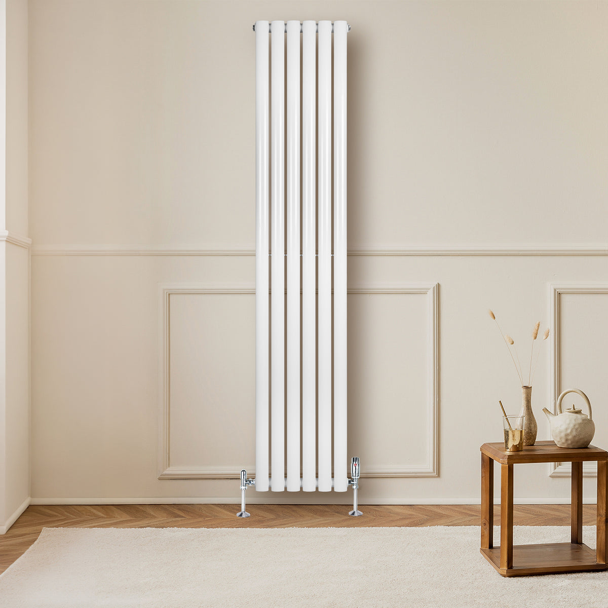 Hochformatiger, weißer Gliederheizkörper mit TRV Chromventilen, elegant an einer hellen Wand montiert, ergänzt durch einen stilvollen Holztisch im Vordergrund