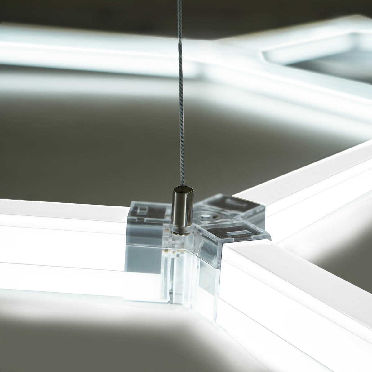 Transparente sechseckige LED-Leuchte mit klaren Kanten und einem stabilen Aufhängesystem, ideal für moderne Garagenbodenfliesen in Grau und Blau