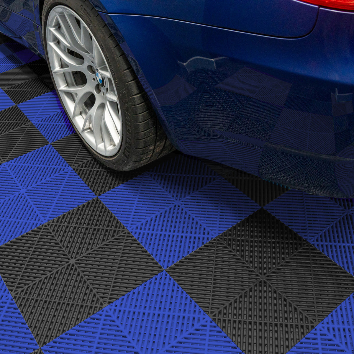 Schwarze und blaue belüftete Garagenbodenfliesen mit rautenförmigem Muster, unter einem blauen Auto, das auf dem glänzenden Boden steht