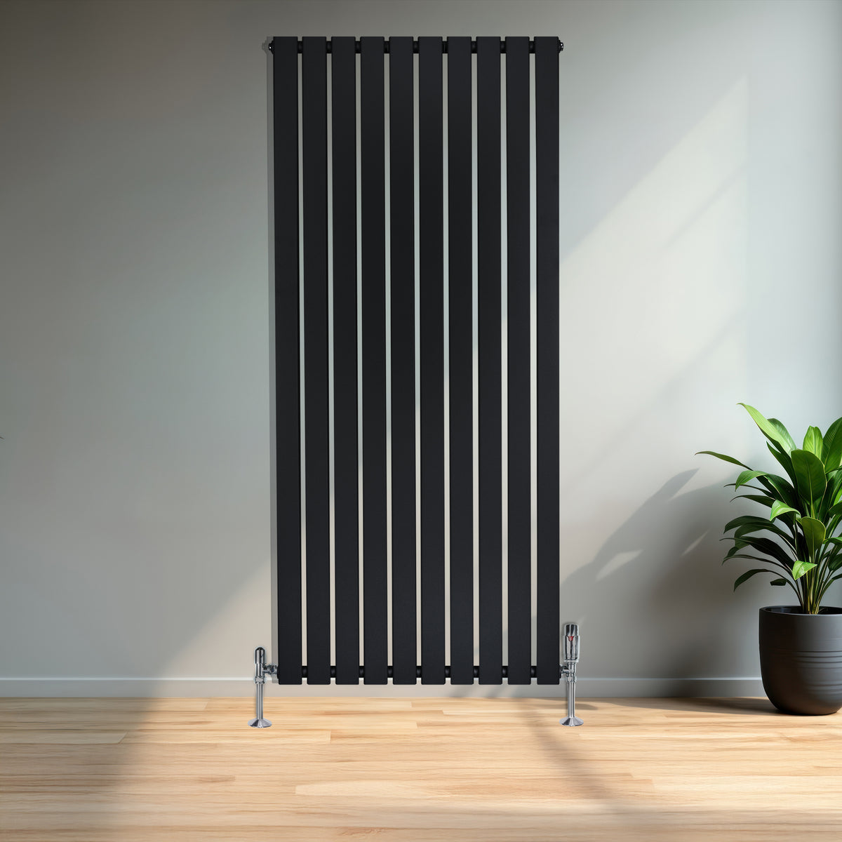 Schwarzer Flachheizkörper mit vertikalen Lamellen, 1600mm x 700mm, elegant in modernem Raum mit Holzfußboden und grüner Pflanze im Hintergrund