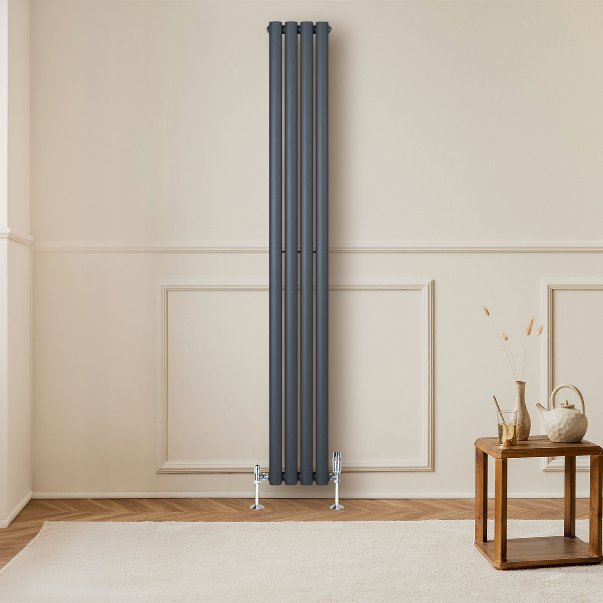 Eleganter anthrazitgrauer Gliederheizkörper mit vier vertikalen Röhren, ideal für moderne Innenräume, auf einem hellen Holzboden vor einer neutralen Wand