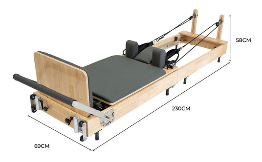 Holz-Pilates-Reformer mit grauem Polster, abnehmbaren Gurten und verstellbaren Seilen, misst 230 cm in der Länge und 69 cm in der Breite