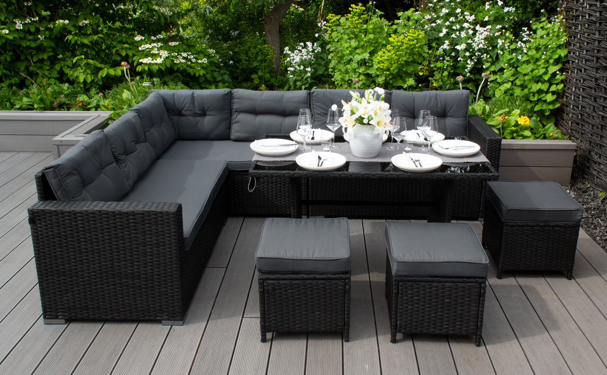 Elegantes, schwarzes Gartenmöbelset aus Rattan mit grauen Kissen, dekoriert mit einem weißen Blumenarrangement und gedecktem Tisch auf einer Holzterrasse