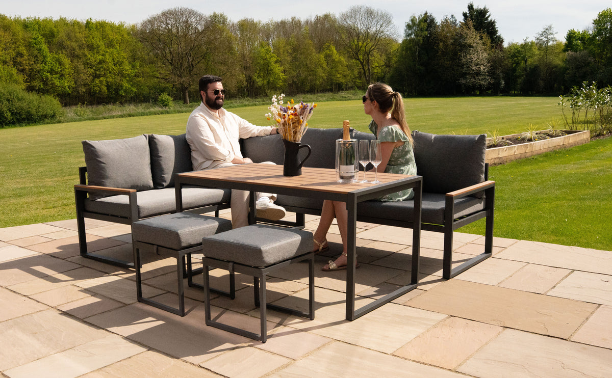Moderne Gartenmöbel aus schwarzem Metall mit grauen Kissen, umgeben von einer grünen Wiese, ideal für entspannte Sommertage im Freien