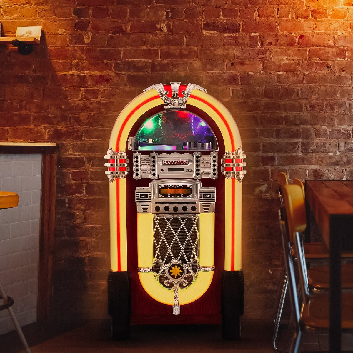 Retro 50er Jahre Jukebox in leuchtendem Rot und Gelb, mit glänzenden Chromdetails, vor einer Backsteinwand, ideal für nostalgische Musikliebhaber