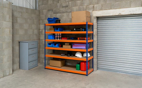 Bunt lackiertes Regalsystem in einer Garage mit verschiedenen Aufbewahrungsboxen, Werkzeugen und Sicherheitshelmen auf stabilen Holzregalen