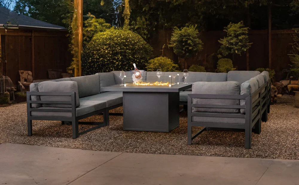 Elegantes graues Aluminium-Gartenmöbel-Set mit bequemen Kissen, umgeben von grünen Pflanzen und sanfter Beleuchtung für eine stilvolle Atmosphäre