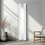Ovaler Röhrenheizkörper in Weiß mit Chrom-Thermostatventilen, elegant an einer Wand montiert, umgeben von einem modernen Raum und Pflanzen
