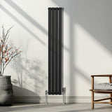 Schwarzer ovaler Röhrenheizkörper mit Chrom-Thermostatventilen, 1600mm x 240mm, elegant an einer Wand, umgeben von natürlichem Licht und minimalistischer Einrichtung