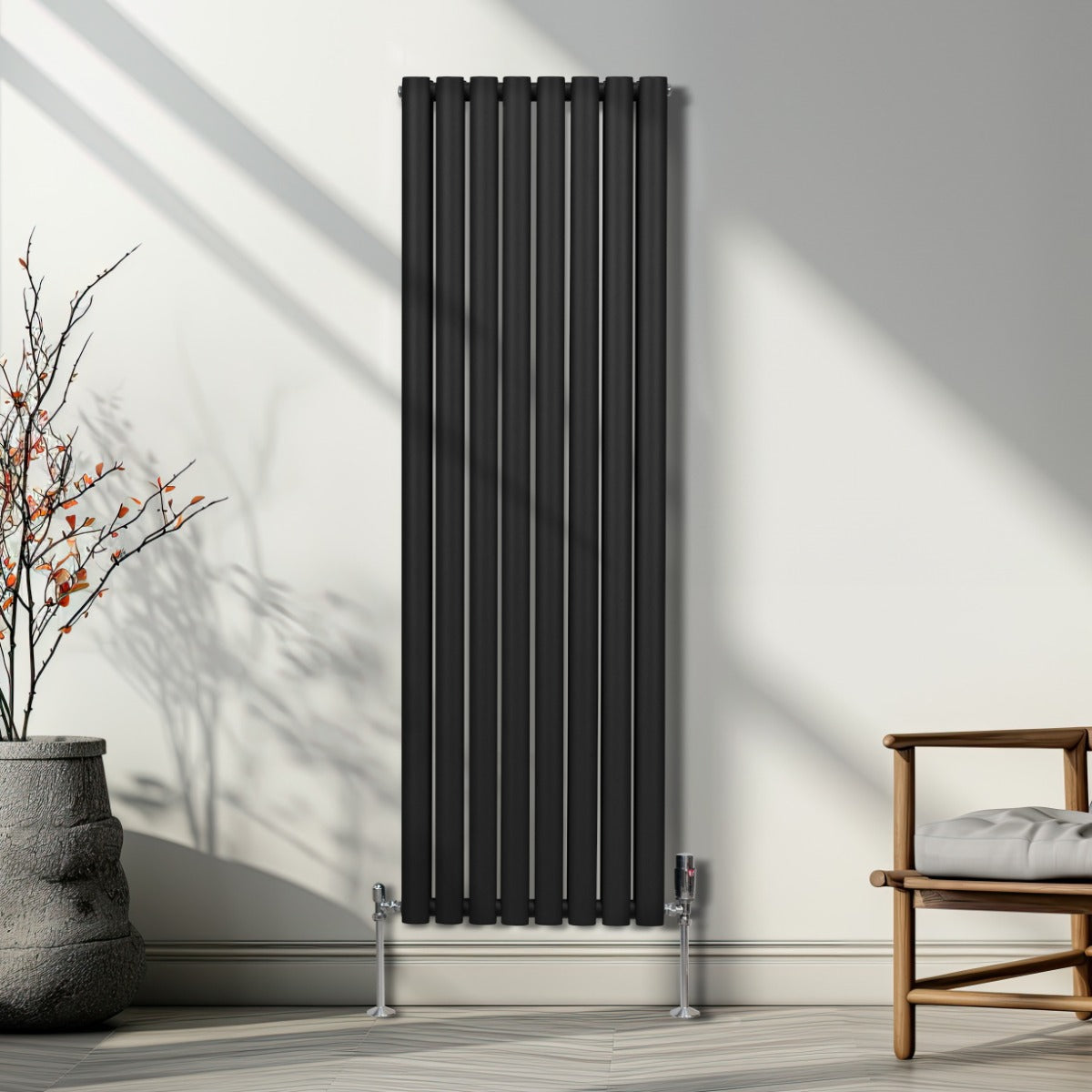 Schwarzer ovaler Röhrenheizkörper mit Chrom-Thermostatventilen, 1600mm x 480mm, an einer hellen Wand, umgeben von minimalistischer Einrichtung