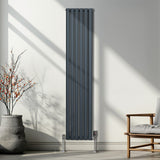 Ovaler Röhrenheizkörper in Anthrazitgrau, 1800mm x 360mm, mit glänzenden Chrom-Thermostatventilen, elegant an einer hellen Wand montiert