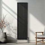 Schwarzer ovaler Röhrenheizkörper mit Chrom-Thermostatventilen, 1800mm x 480mm, elegant an einer hellen Wand, umgeben von minimalistischer Einrichtung