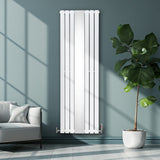 Weißer Heizkörper mit vertikalen Lamellen und Chrom-Thermostatventilen, elegant an einer grauen Wand, umgeben von einem modernen Raum und einer Pflanze