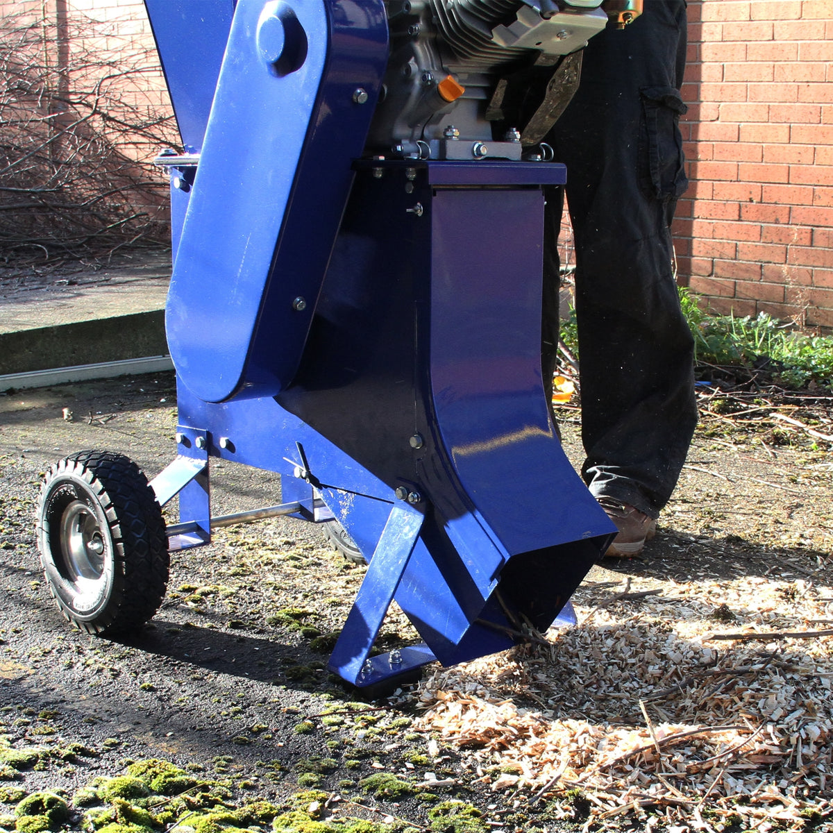 Der T-Mech 15PS Holzhäcksler in leuchtendem Blau mit robustem Gehäuse und großen Rädern, der Holzspäne auf dem Boden zerkleinert