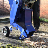 Der T-Mech 15PS Holzhäcksler in leuchtendem Blau mit robustem Gehäuse und großen Rädern, der Holzspäne auf dem Boden zerkleinert