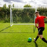 Fußballtor 2,4m x 1,8m aus robustem Kunststoff, auf grünem Rasen, mit einem Spieler in rotem Trikot, der einen bunten Fußball schießt
