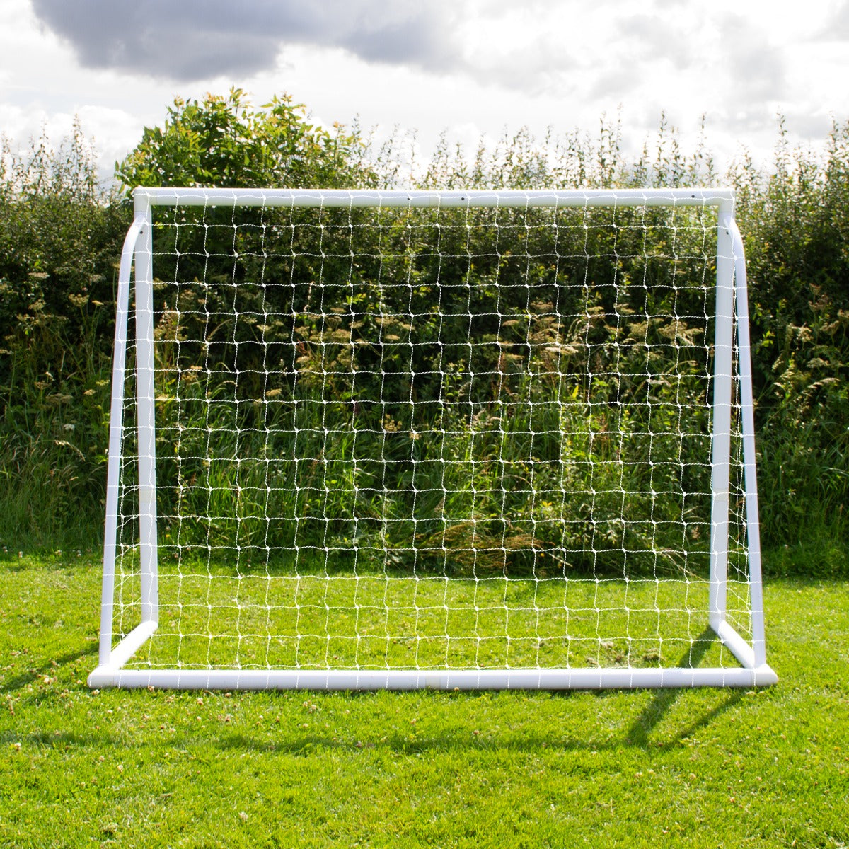 Fußballtor in Weiß mit stabilen Netz, 2,4m x 1,8m, auf grünem Rasen vor einer bewachsenen Kulisse, ideal für Training und Freizeitspiele
