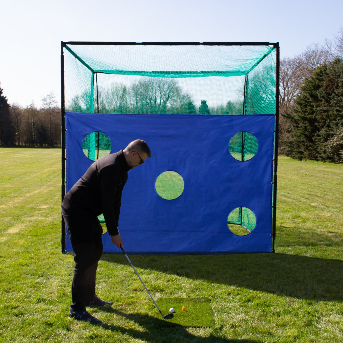 Golfkäfignetz mit blauer Zielscheibe und grünen Netzen, ideal für das Training, zeigt einen Golfer, der auf den Ball zielt, auf einer grünen Wiese
