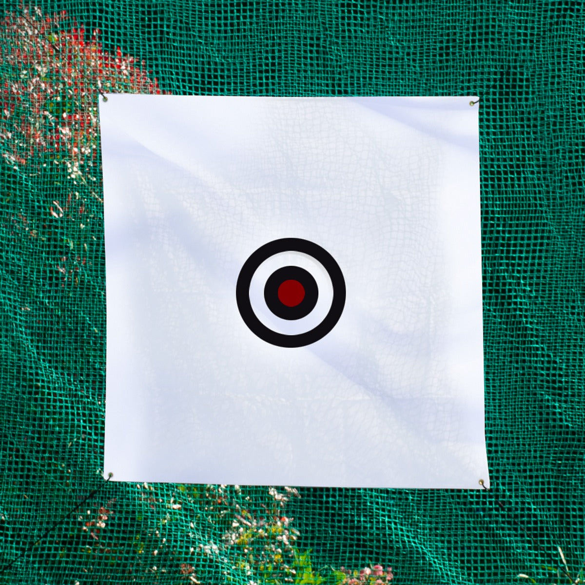 Ein weißes Ziel mit einem schwarzen und roten Ring, aufgehängt vor einem grünen Golfkäfignetz, ideal für das Golftraining und Zielübungen