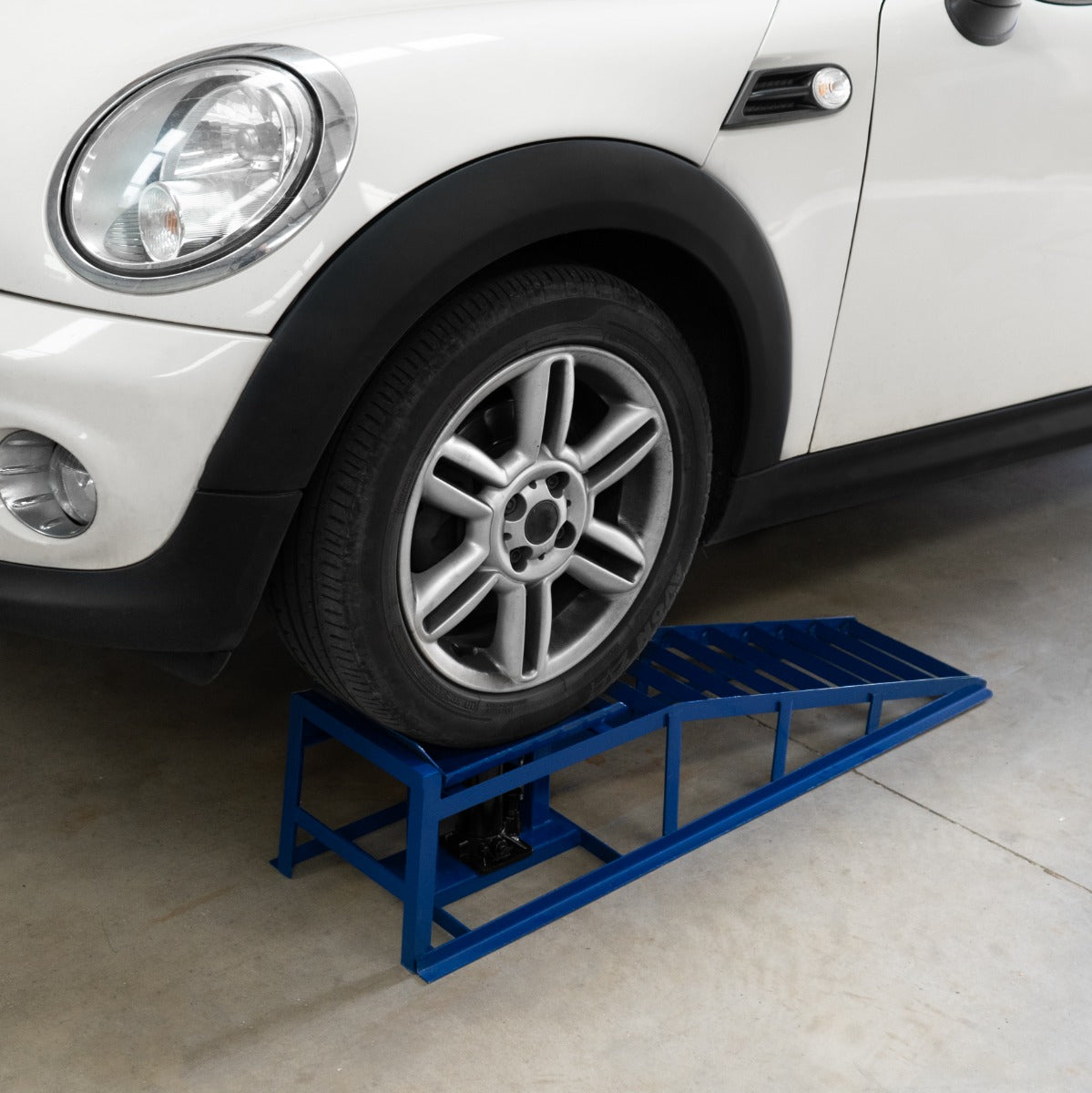 Auffahrrampe in leuchtendem Blau mit stabiler Metallkonstruktion, unterstützt ein Auto mit einem hydraulischen Wagenheber für einfache Wartung