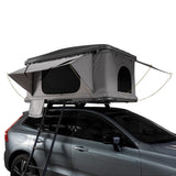 Grau gefärbtes Auto-Dachzelt mit seitlichen Fenstern und einem stabilen Gestell, montiert auf einem silbernen SUV, ideal für Campingabenteuer