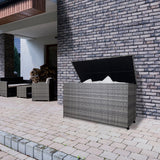 Grau geflochtene Rattan Kissenbox mit einem stabilen Deckel, ideal für die Aufbewahrung von Kissen und Decken im Außenbereich, auf einem gepflasterten Boden