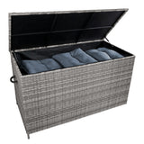 Grau geflochtene Rattan-Kissenbox mit offenem Deckel, gefüllt mit blauen Kissen, ideal zur Aufbewahrung und als stilvolles Gartenmöbel