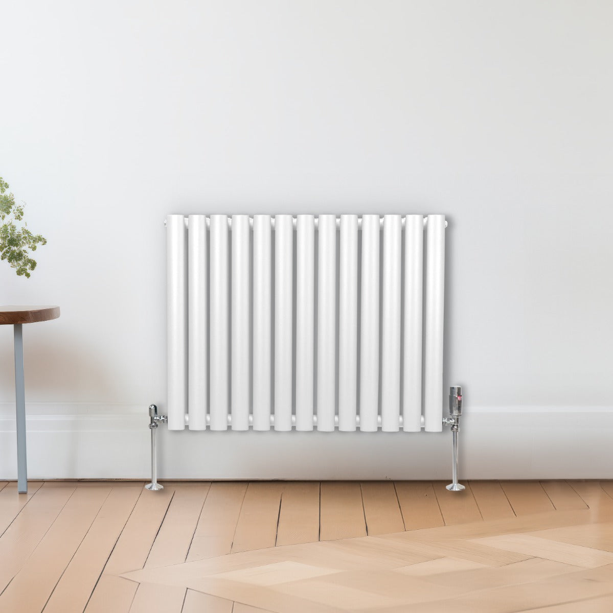 Ovaler Röhrenheizkörper in Weiß, 600mm x 780mm, mit glatten, vertikalen Röhren und glänzenden, verchromten Ventilen, vor einem hellen Raum mit Holzfußboden
