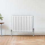 Ovaler Röhrenheizkörper in Weiß, 600mm x 780mm, mit glatten, vertikalen Röhren und glänzenden, verchromten Ventilen, vor einem hellen Raum mit Holzfußboden