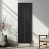 Ovaler Röhrenheizkörper in Schwarz, 1800mm x 600mm, mit vertikalen Lamellen und eleganten Füßen, ideal für moderne Wohnräume und effiziente Wärmeverteilung