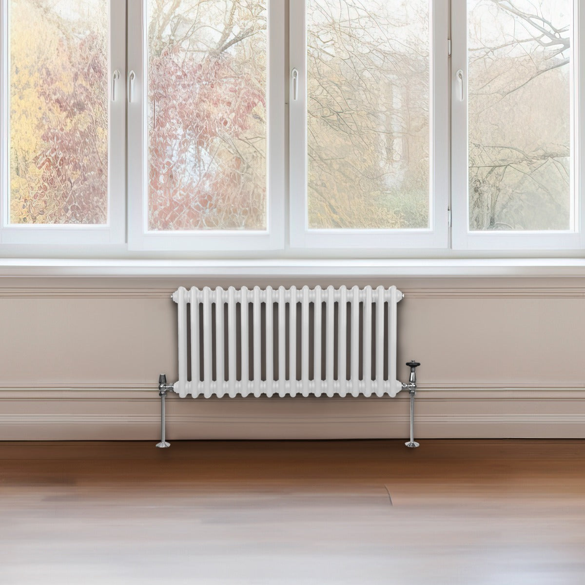Traditioneller 2-Spalten-Heizkörper in Weiß, 300 x 832 mm, mit glatten, vertikalen Lamellen und verchromten Ventilen, vor einem großen Fenster platziert